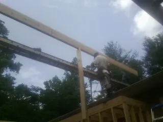 Carpenter setting a ridge beam over a new addition frame — Ice Dam Removal by Roofing Brothers in Perth Amboy