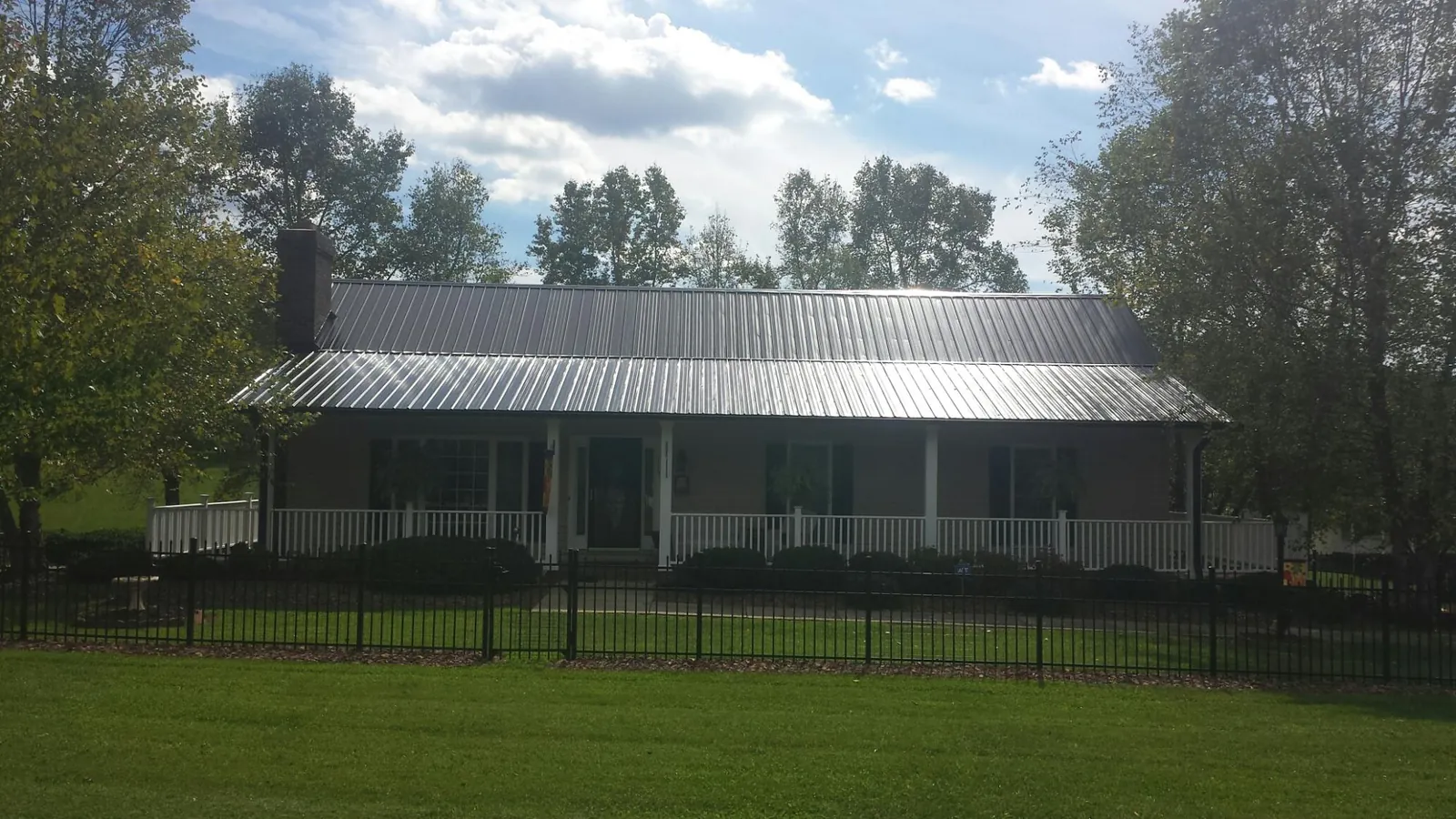 Gray metal roof on a brick ranch with a full width front porch — Gutter Guard Installation work by our crew in Perth Amboy