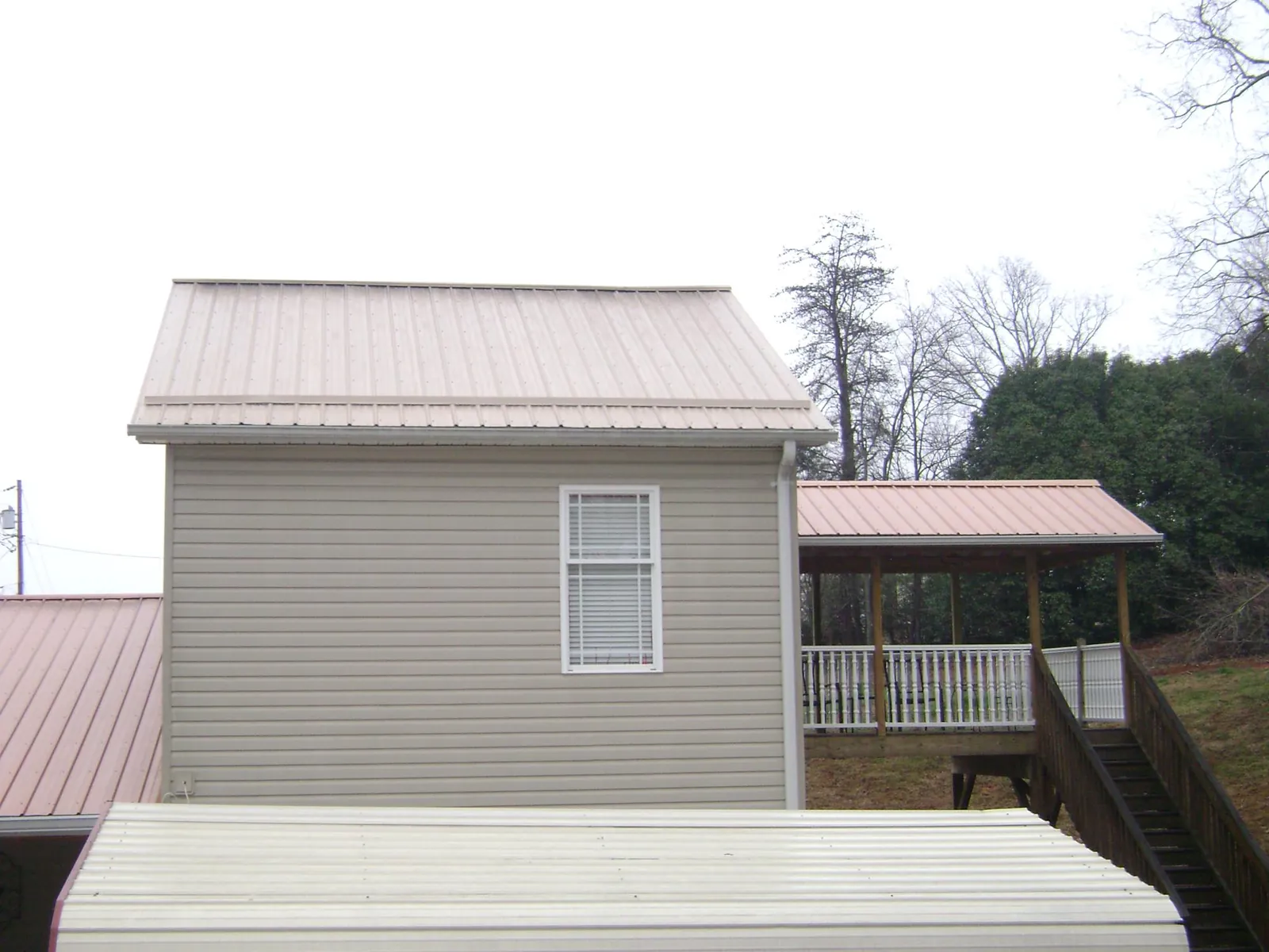 Tan metal roofs on a two story addition and attached porch, from a Roof Replacement job in Perth Amboy