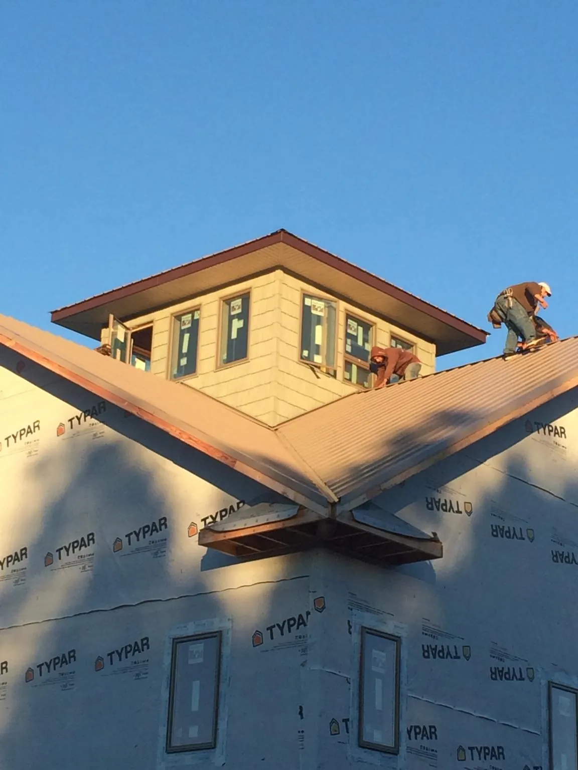 Roofers working around a rooftop cupola on a new metal roof at sunset — Roof Waterproofing in Perth Amboy by Roofing Brothers